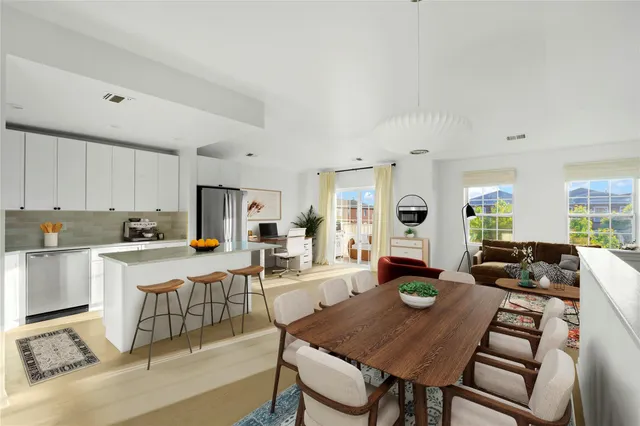 a living room with stainless steel appliances furniture a rug and a kitchen view