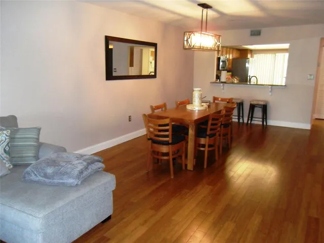 a dining room with wooden floor a chandelier a wooden table and chairs