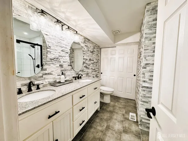 a bathroom with a double vanity sink toilet and shower
