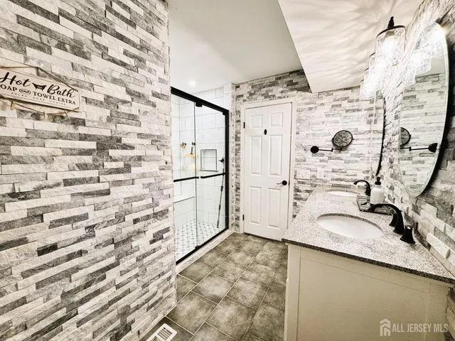 a bathroom with a granite countertop sink a mirror and shower