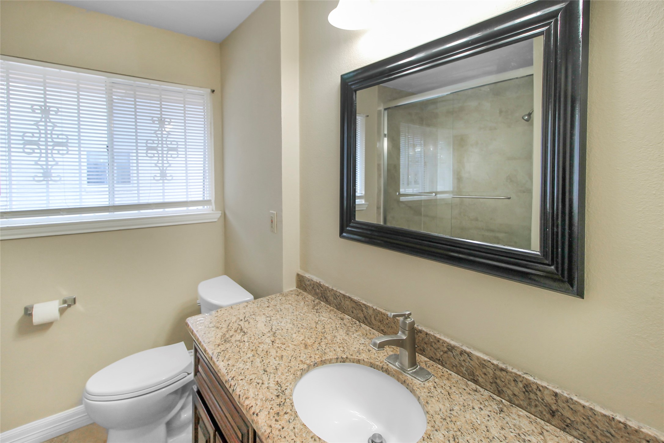 5738 Willowbend Boulevard Houston, TX 77096 - Photo 23 of 28 a bathroom with a granite countertop toilet a sink and mirror
