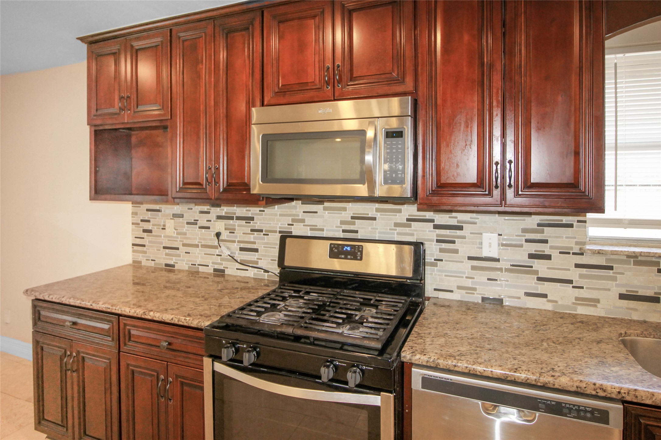 5738 Willowbend Boulevard Houston, TX 77096 - Photo 10 of 28 a kitchen with granite countertop wooden cabinets and a stove top oven