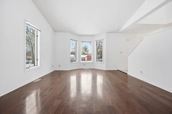 an empty room with wooden floor cabinet and windows