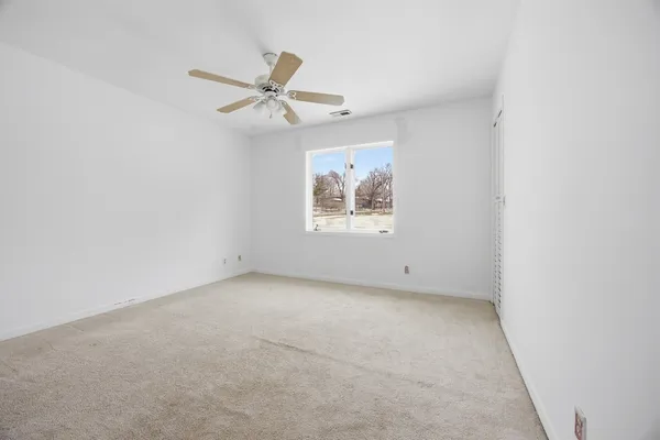 an empty room with windows and fan