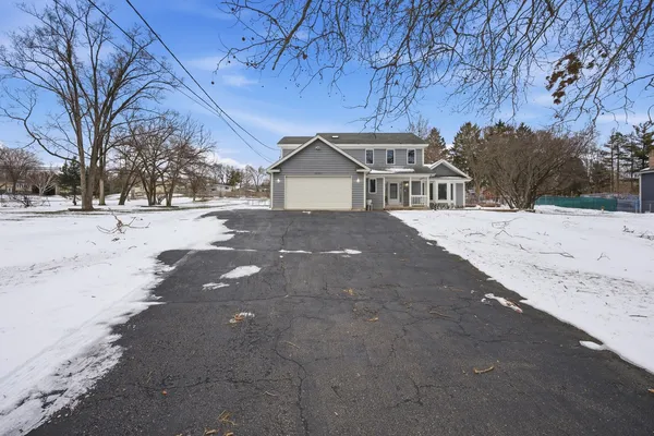 a front view of a house with a yard covered in snow