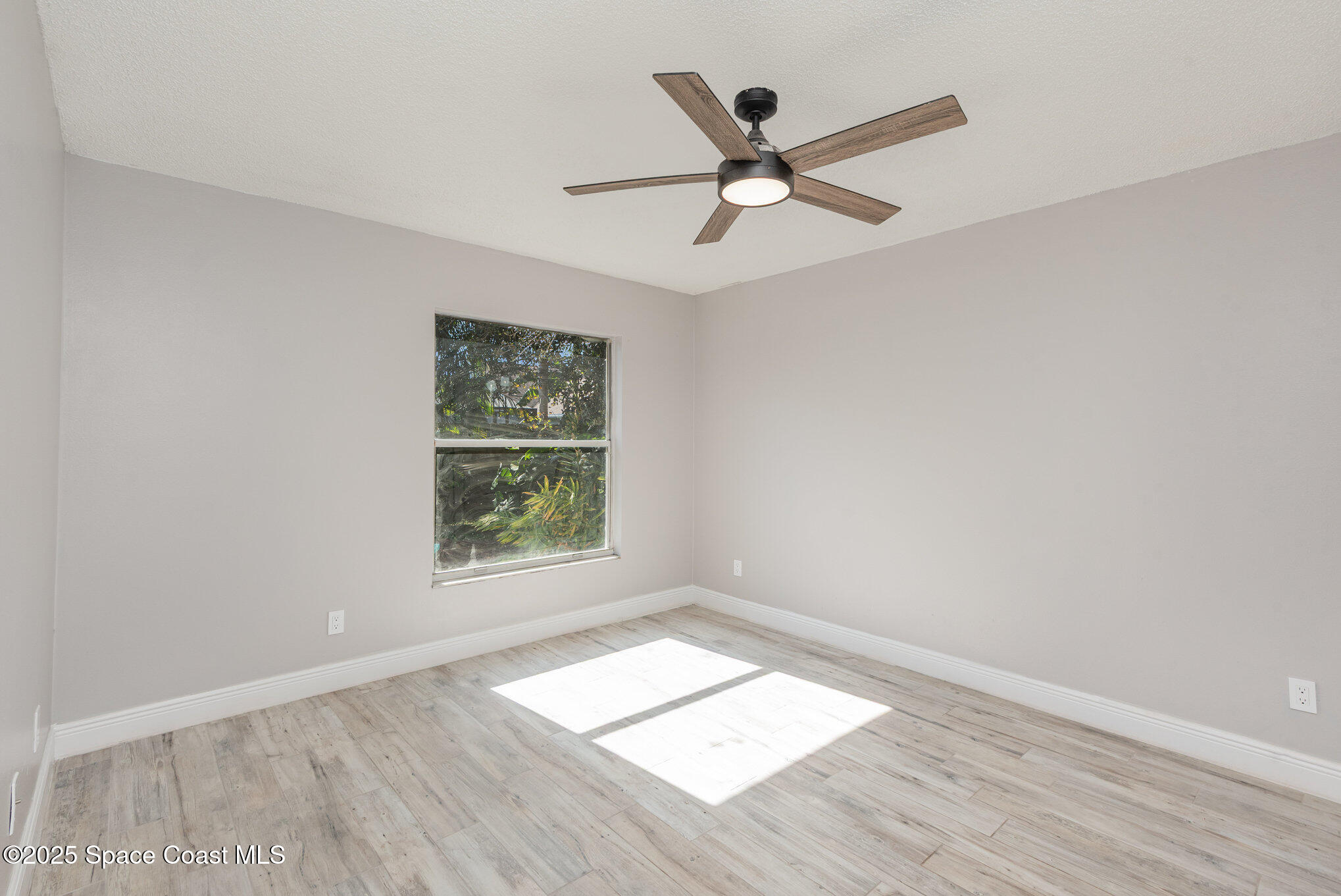 1045 Jacaranda Circle Rockledge, FL 32955 - Photo 12 of 32 an empty room with wooden floor fan and windows