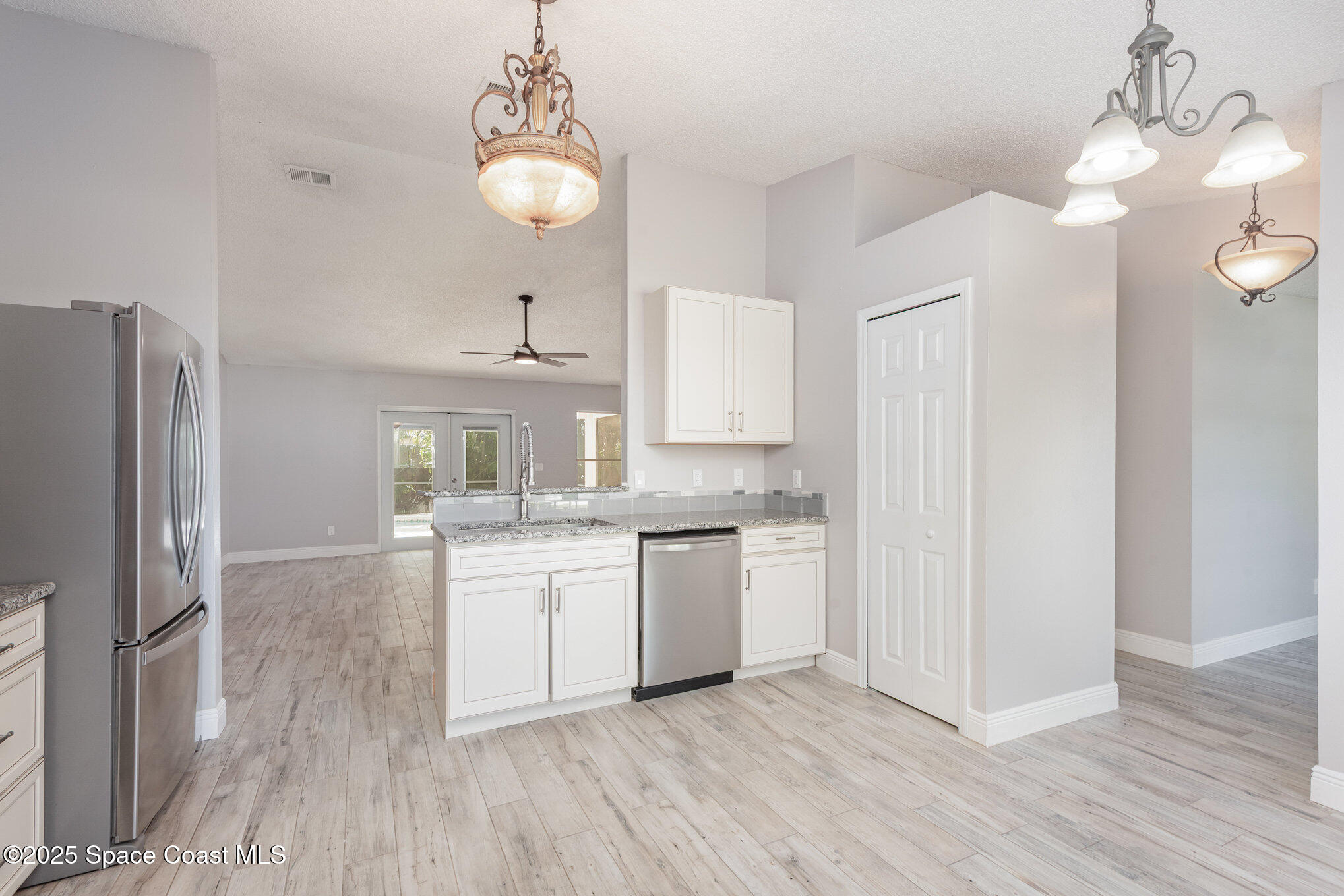 1045 Jacaranda Circle Rockledge, FL 32955 - Photo 8 of 32 a kitchen with kitchen island granite countertop a refrigerator a sink dishwasher a stove and white cabinets with wooden floor