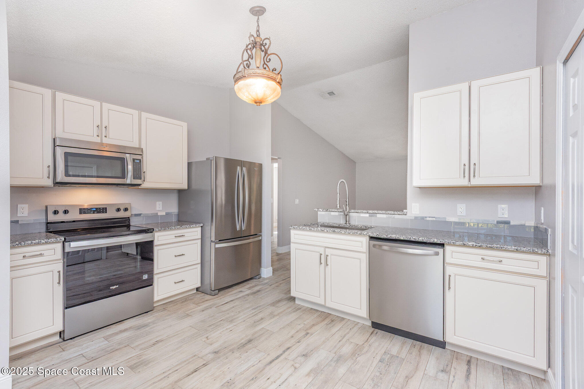 1045 Jacaranda Circle Rockledge, FL 32955 - Photo 9 of 32 a kitchen with stainless steel appliances granite countertop a stove top oven a sink dishwasher a refrigerator and cabinets with wooden floor