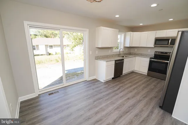 a kitchen with a refrigerator wooden floor sink and a large window