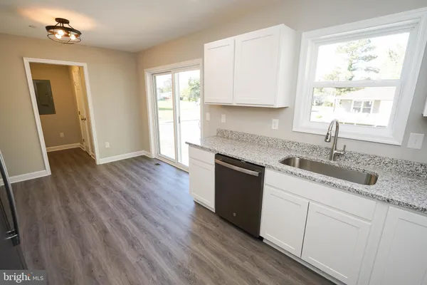 a kitchen with granite countertop wooden floors white cabinets and sink