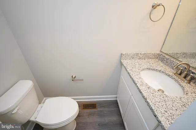 a bathroom with a granite countertop toilet and a sink