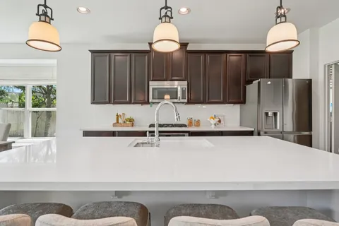 a kitchen with a stove a sink and wooden floor