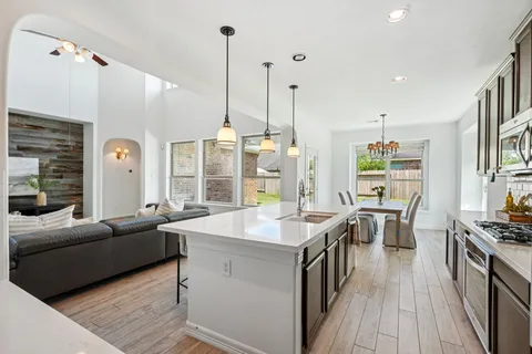 a kitchen with stainless steel appliances granite countertop a refrigerator a sink dishwasher a stove a microwave oven with cabinets and wooden floor