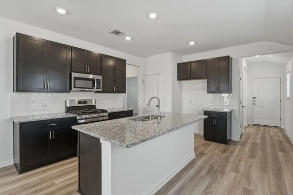 a kitchen with stainless steel appliances granite countertop a stove a sink and a microwave