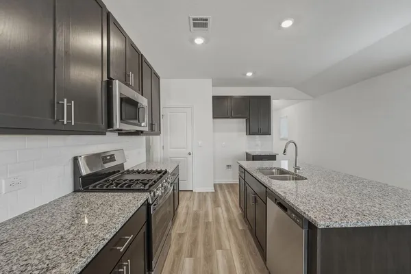 a kitchen with stainless steel appliances granite countertop a sink stove microwave and cabinets