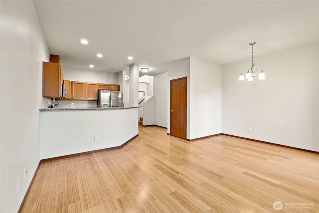 a view of a kitchen with kitchen island wooden floor stainless steel appliances and cabinets