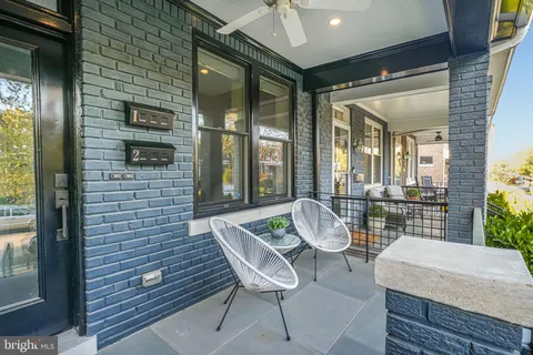 a balcony with couple of chairs and a potted plant