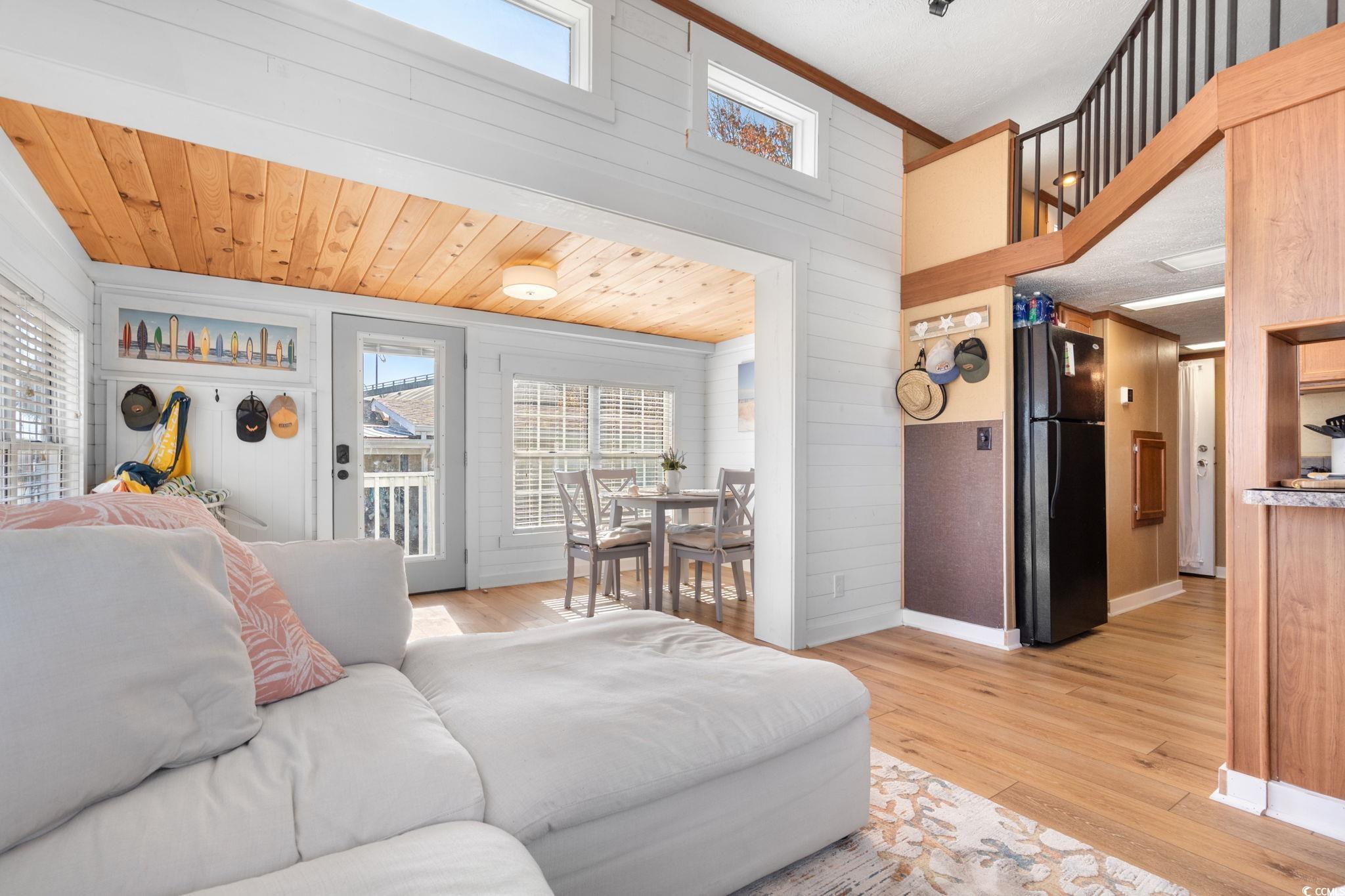 137 Riptide Circle North Myrtle Beach, SC 29582 - Photo 9 of 32 Living room with wood walls, light wood-type flooring, wood ceiling, a high ceiling, and crown molding