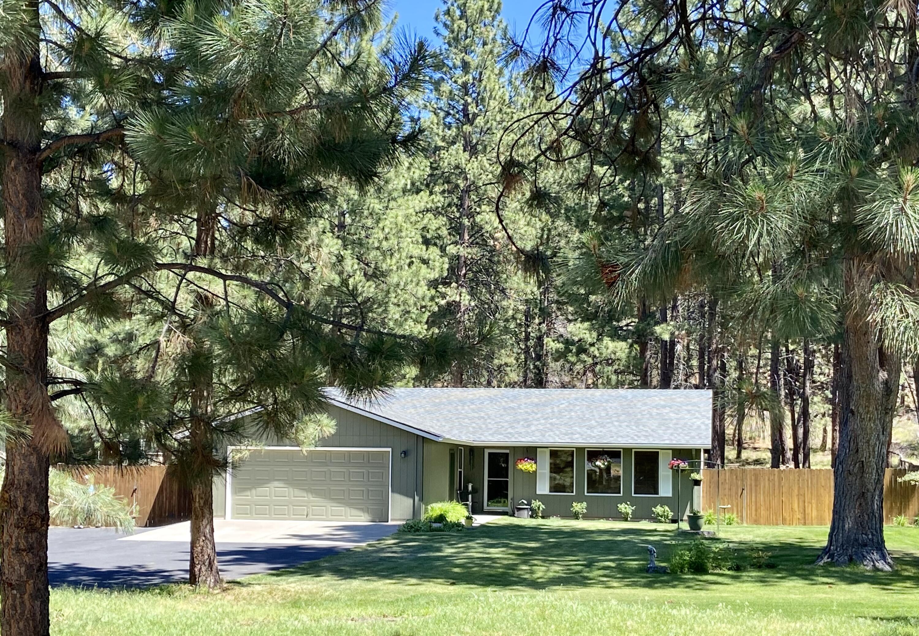 60218 Agate Road Bend, OR 97702 - Photo 1 of 19 a view of a white house with a big yard and large trees