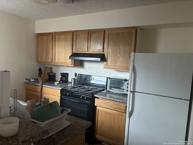 a kitchen with stainless steel appliances granite countertop a stove a refrigerator and a stove