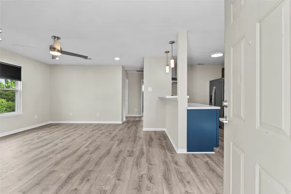 a view of a hallway with wooden floor and a bathroom