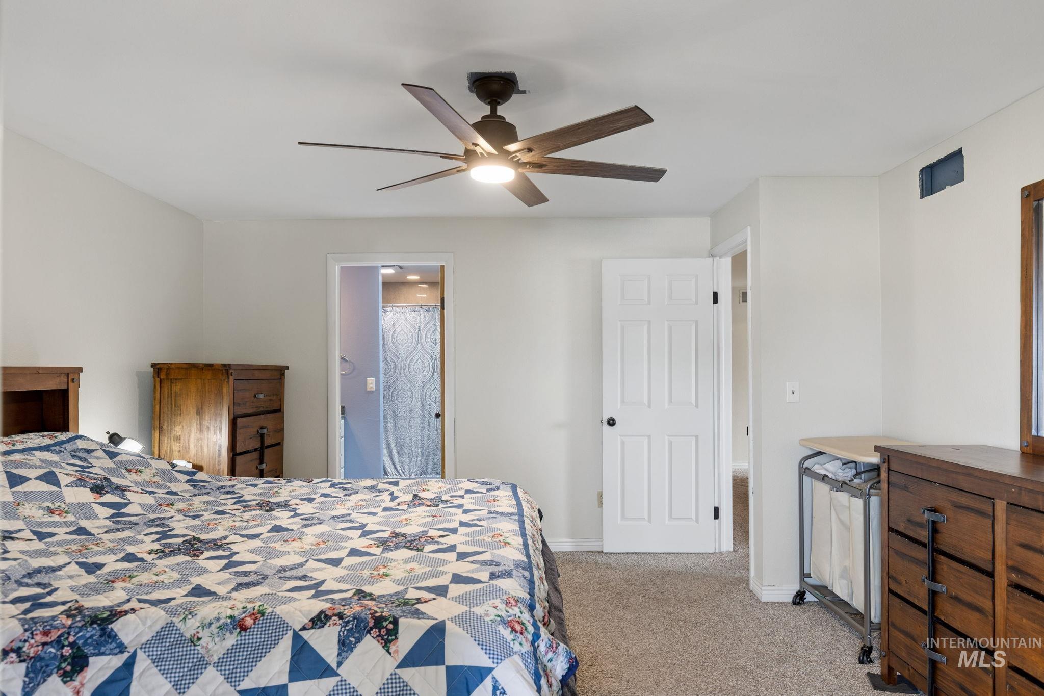 18338 Pride Lane Caldwell, ID 83607 - Photo 24 of 50 Spacious bedroom featuring light-colored walls, carpet flooring, a dark-toned ceiling fan with integrated lighting, and multiple panel doors