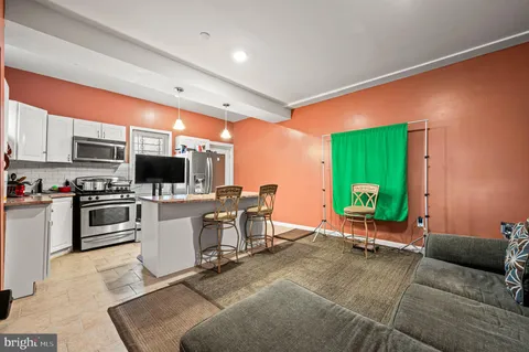 a living room with furniture a flat screen tv and kitchen view