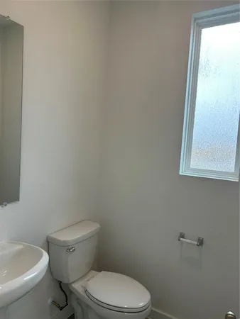 a white toilet sitting next to a white sink and a window