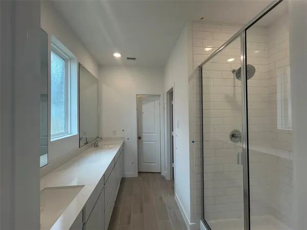 a bathroom with a double vanity sink a large mirror and shower