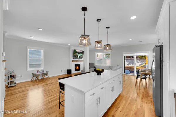 a kitchen with stainless steel appliances kitchen island granite countertop a table chairs in it and white cabinets