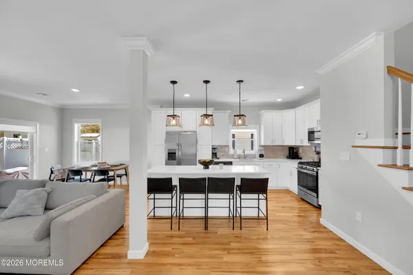 a living room with couches and kitchen view with wooden floor
