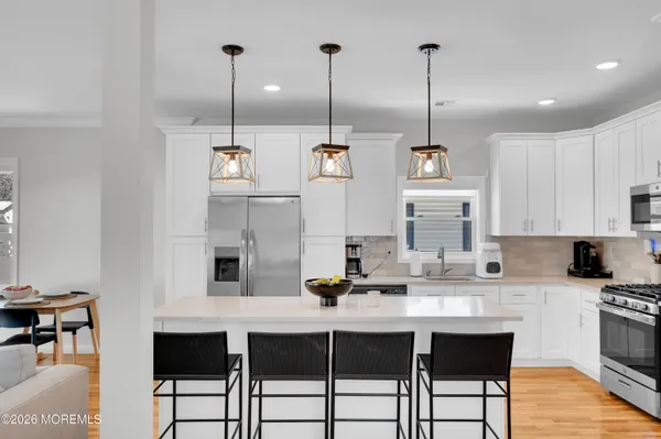 a large white kitchen with stainless steel appliances lots of counter space and breakfast area