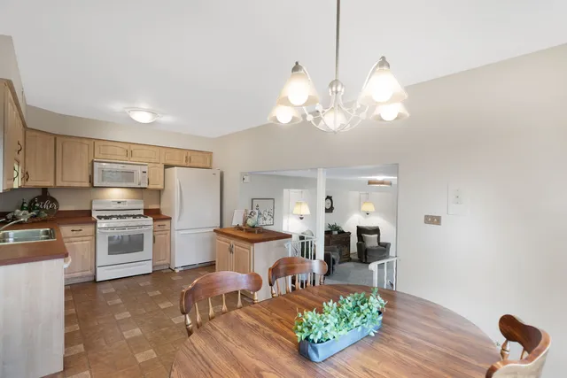 a living room with stainless steel appliances furniture a chandelier and a view of kitchen