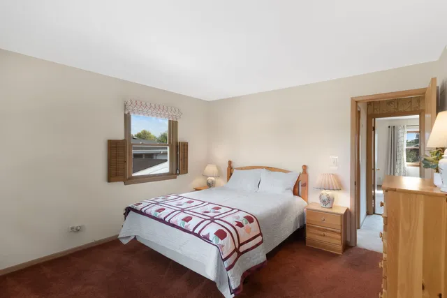 a bedroom with a bed lamp on table and a window