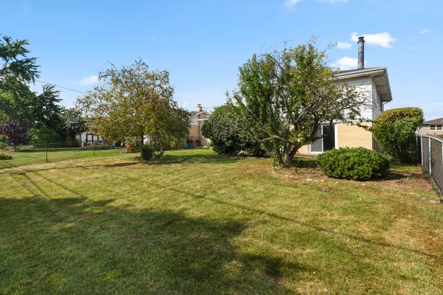 a view of a patio with table and chairs potted plants and large tree