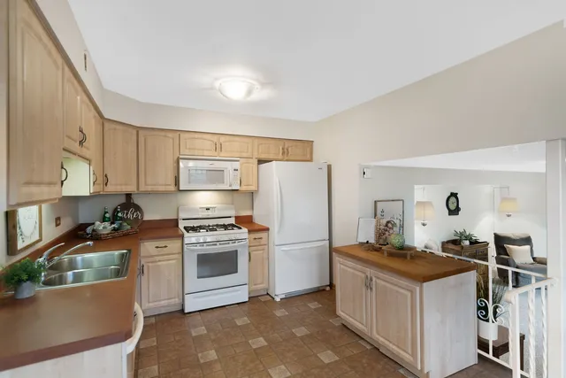 a kitchen with stainless steel appliances granite countertop a stove top oven a refrigerator a sink and dishwasher with white countertops