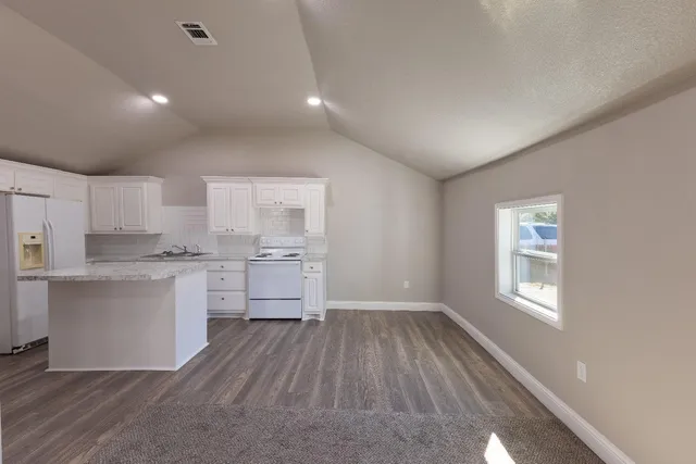a kitchen with white cabinets and wooden floor