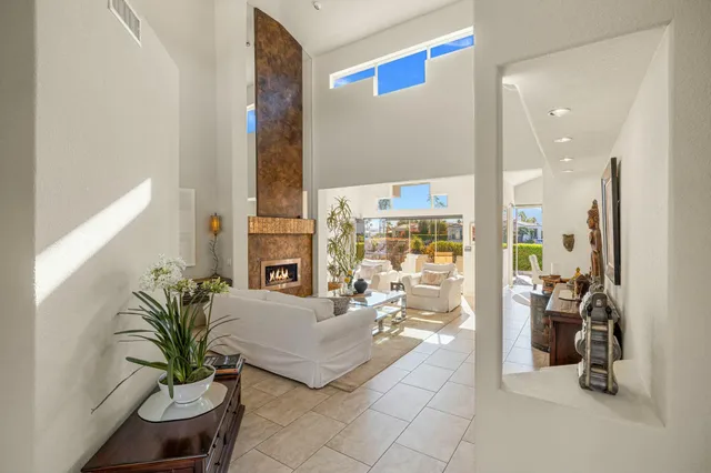 a living room with furniture floor to ceiling window and a potted plant
