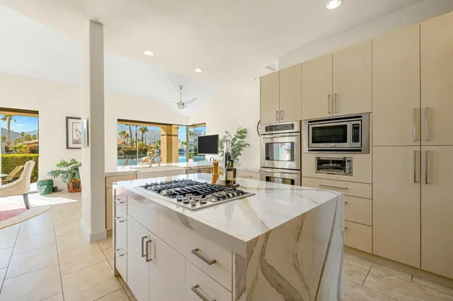 a kitchen with stainless steel appliances kitchen island granite countertop a stove refrigerator and a sink