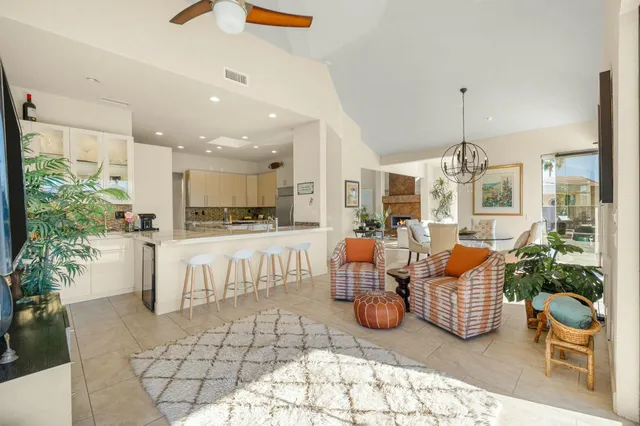 a living room with furniture a chandelier and kitchen view