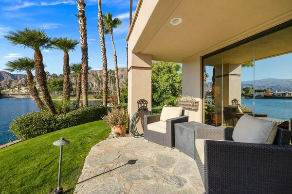 a view of a patio with couches potted plants and a large tree