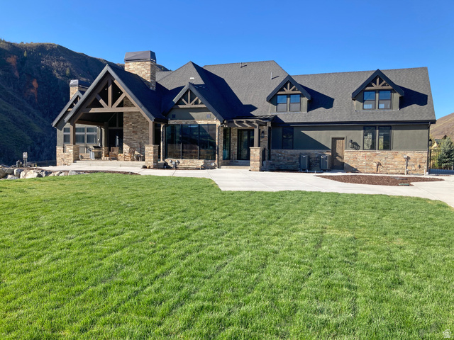 259 Meadow Drive Springville, UT 84663 - Photo 3 of 62 View of rear of property featuring stone siding, a front lawn, a chimney, a mountain view, and stucco siding