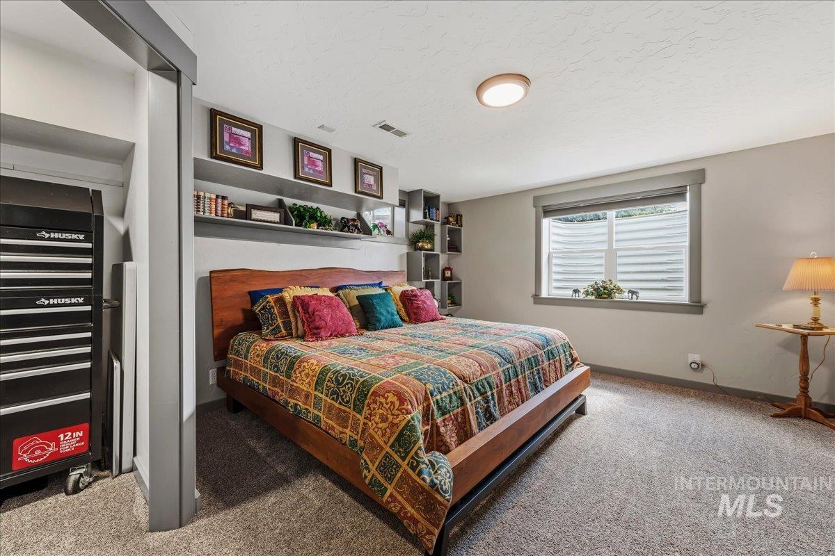 6323 Foothill Road Star, ID 83669 - Photo 20 of 50 Carpeted bedroom featuring a window with blinds, recessed shelving, and a wood-frame bed
