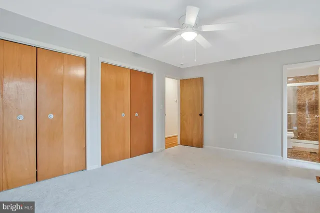 a view of a room with a large window and ceiling fan