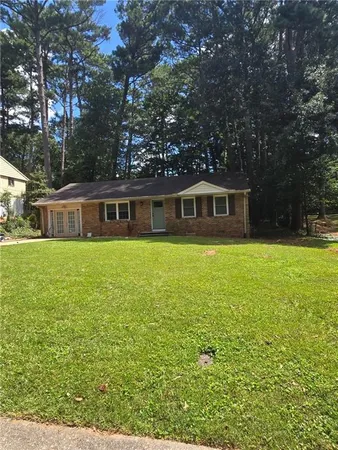 a view of house with yard outdoor seating and covered with trees