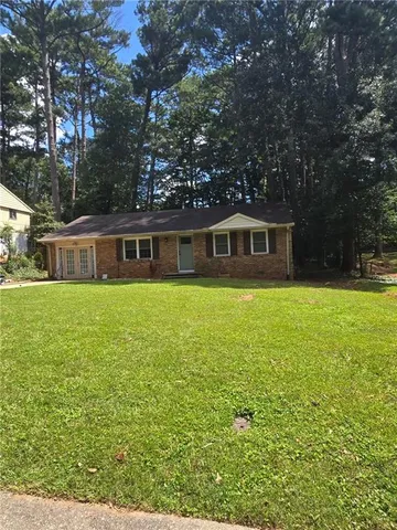 a view of house with yard outdoor seating and covered with trees