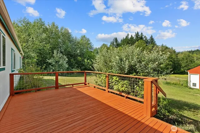 a view of trees and deck with wooden floor and fence