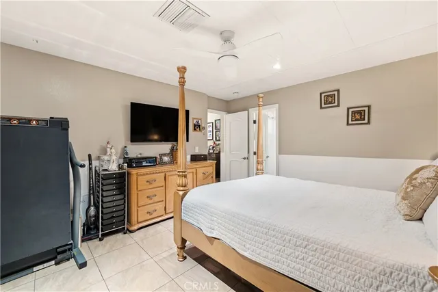 a bedroom with a bed flat screen tv and windows