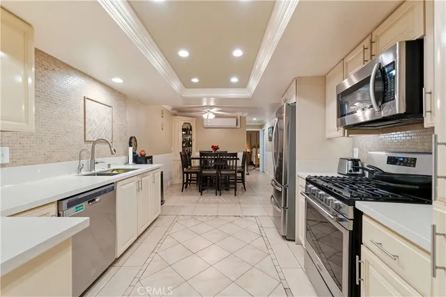 a kitchen with stainless steel appliances a sink a stove a refrigerator cabinets and a dining table