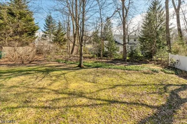 a view of house with backyard and trees in the background